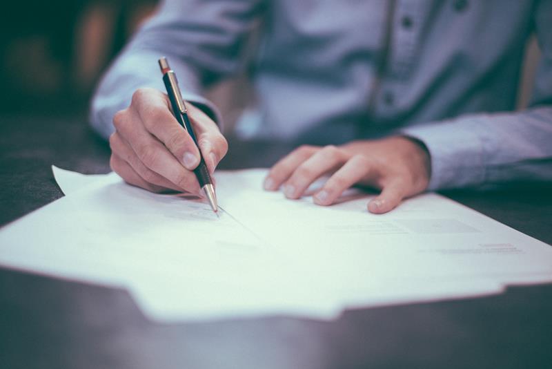 homem assinando papel representando escritura de inventário